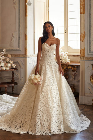Elegant lace ballgown wedding dress with off-the-shoulder neckline and full skirt, styled in a classic romantic setting.