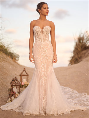 Strapless fit and flare wedding dress with sheer corset bodice and lace detailing, styled outdoors with a train.