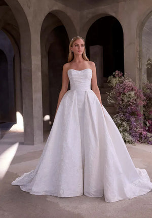 Classic strapless ballgown wedding dress with structured bodice and full skirt, styled with floral background.