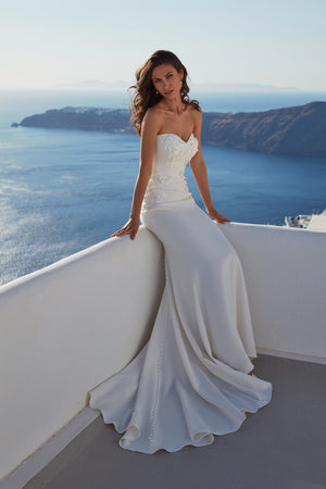 Strapless fit and flare wedding dress with clean satin finish and buttoned back detail, overlooking ocean view.